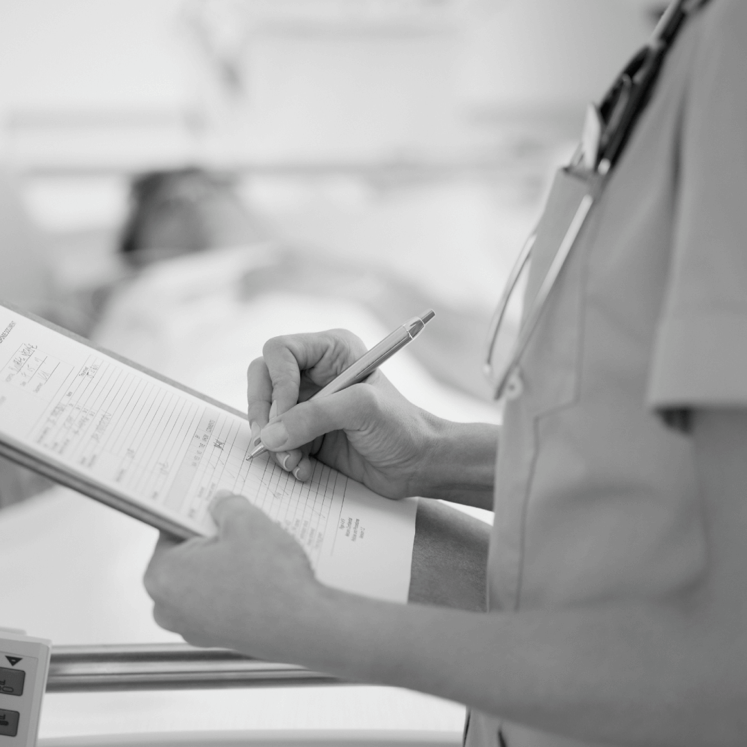 A nurse making notes about a patient lying to 